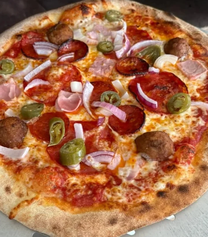Paul's pizza with a golden crust and mixed toppings, photographed at the oven